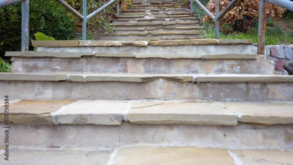Climbing outdoor straight old stone steps with metal railing of an open panoramic platform. Green and orange vegetation around. No people. Slow motion.