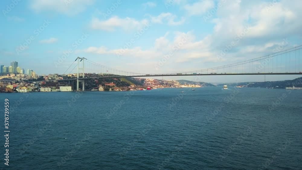The Bosphorus Bridge in Istanbul from a bird's eye view. Blue waves of the strait between Europe and Asia in clear weather. The Bosphorus Bridge in Istanbul from a bird's eye view. Blue waves of the strait between Europe and Asia in clear weather.