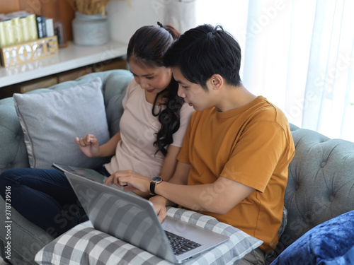 Couple using digital devices while relaxed sitting on sofa in living room