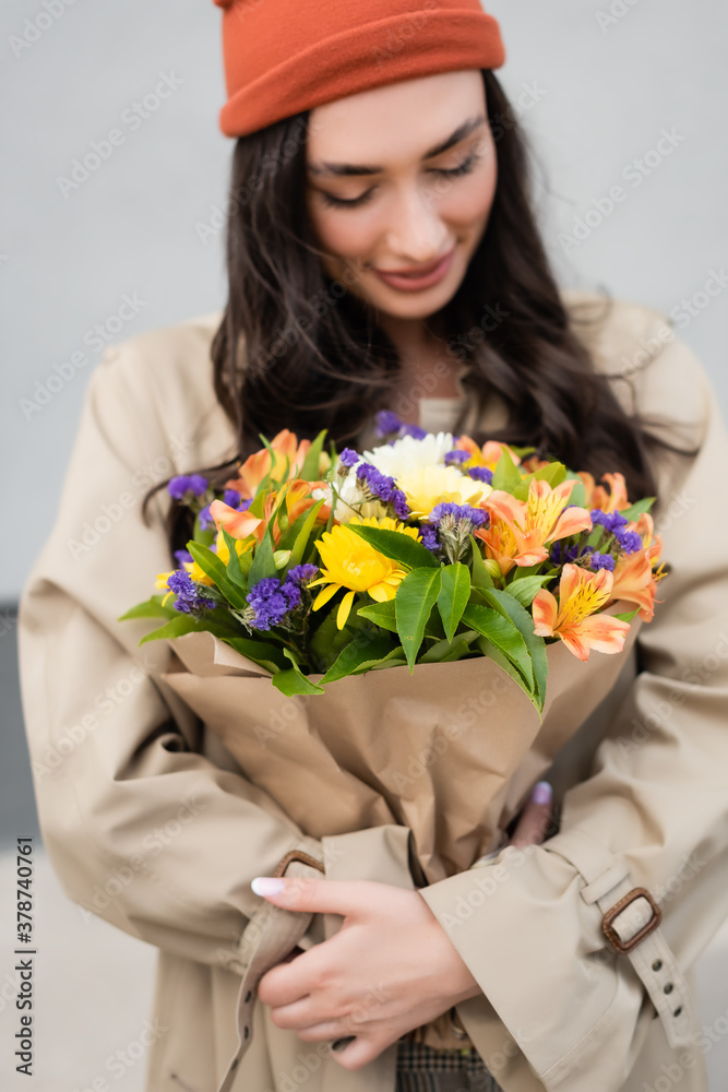 selective focus of trendy woman looking at bouquet of flowers selective focus of trendy woman looking at bouquet of flowers