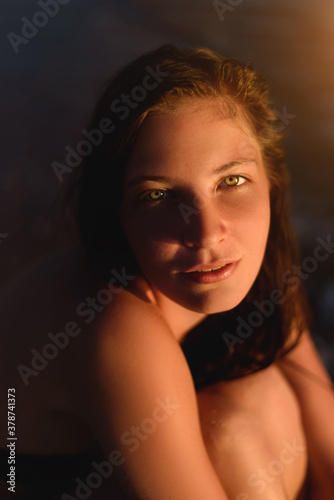 Close up portrait of beautiful happy young woman sitting on beach.