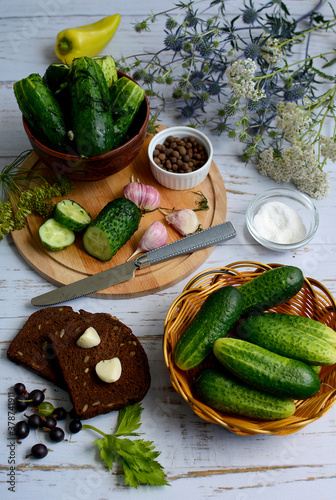 Cucumbers, garlic, herbs, spices on a cutting board and in a basket on a light wooden table