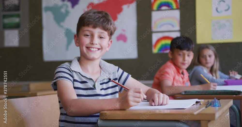 Boy smiling while sitting on his desk at school Boy smiling while sitting on his desk at school
