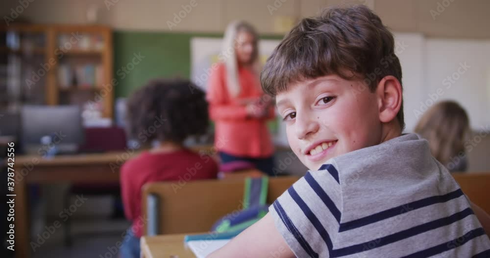 Boy smiling while sitting on his desk at school Boy smiling while sitting on his desk at school