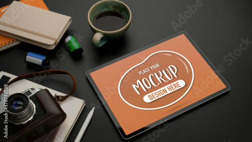 Mock up tablet on black table with camera, stationery, supplies and coffee cup