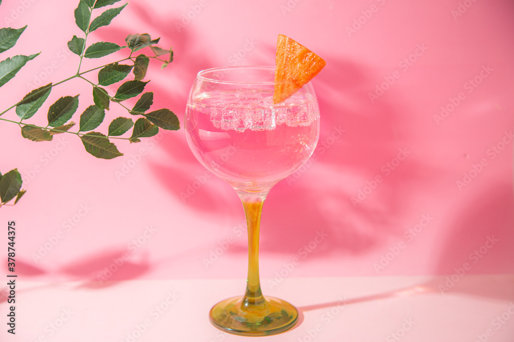 gin and tonic glass on pink background