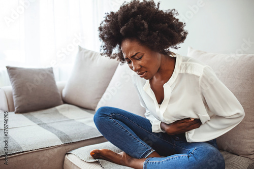 Shot of a young woman suffering from stomach cramps. Woman with abdomen problems in bed, she use hands to massage painful place. Shot of a young woman suffering from stomach cramps at home