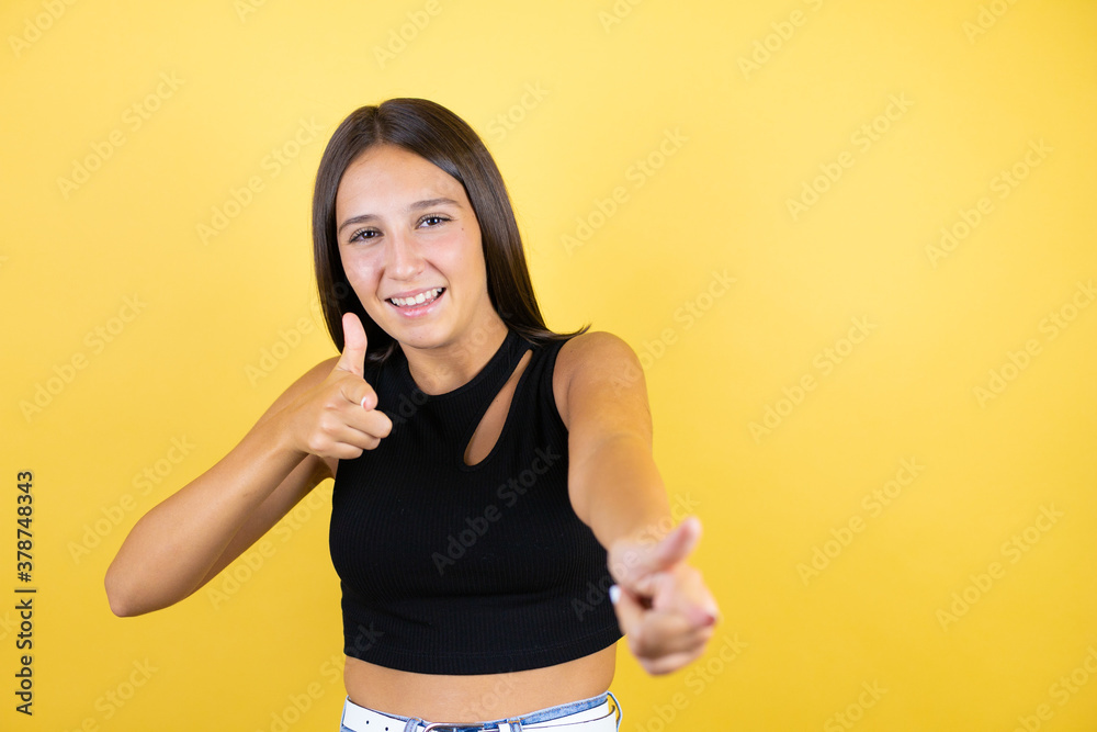 Beautiful young girl kid over isolated yellow background pointing to you and the camera with fingers, smiling positive and cheerful Beautiful young girl kid over isolated yellow background pointing to you and the camera with fingers, smiling positive and cheerful