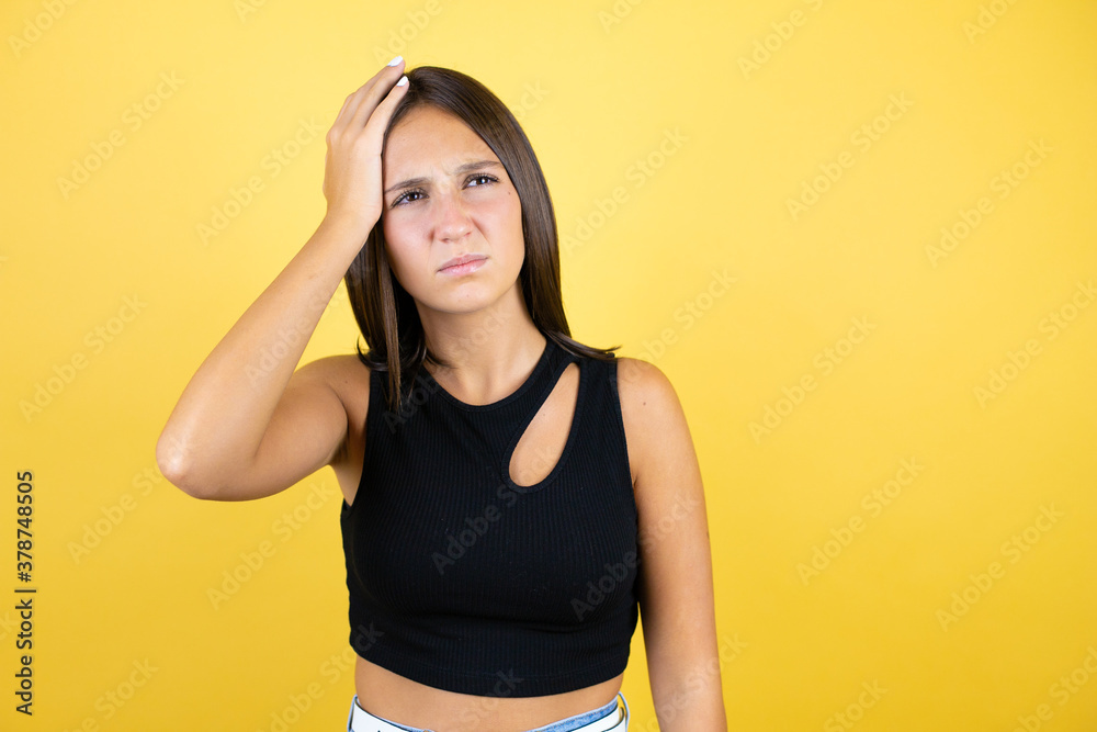 Beautiful young girl kid over isolated yellow background putting one hand on her head smiling like she had forgotten something annoyed Beautiful young girl kid over isolated yellow background putting one hand on her head smiling like she had forgotten something annoyed