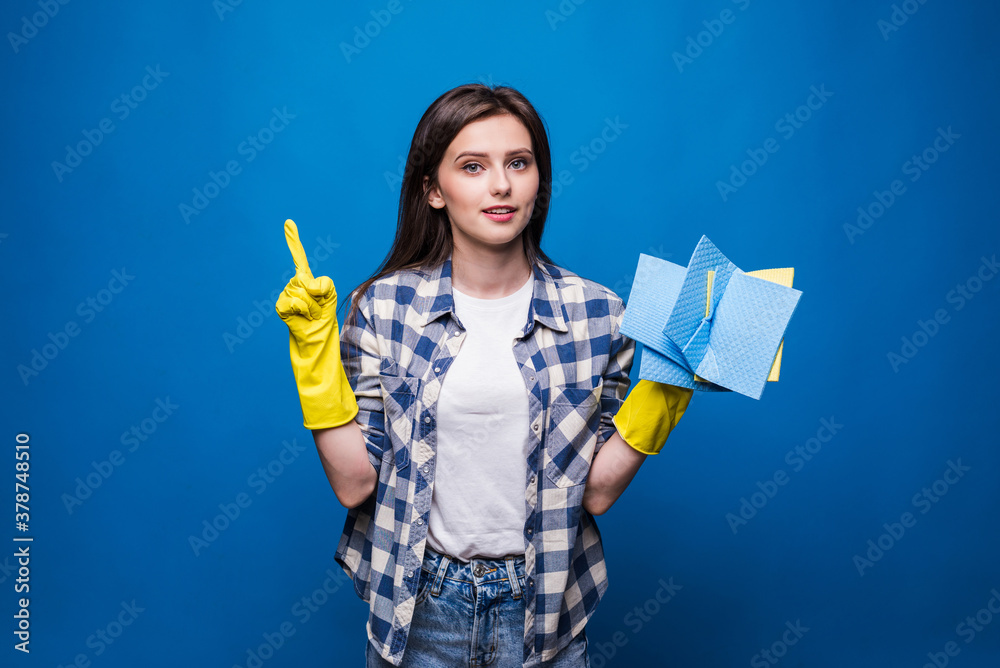 Young woman in apron with finger up isolated on blue background. Good idea to clean. Cleaning concept Young woman in apron with finger up isolated on blue background. Good idea to clean. Cleaning concept