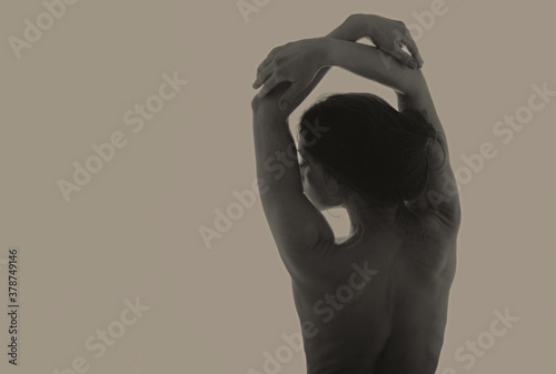 Beautiful sexy young woman holding elegant hands above the head with healthy slim body. Closeup portrait. Back view. Art color. Vogue style.