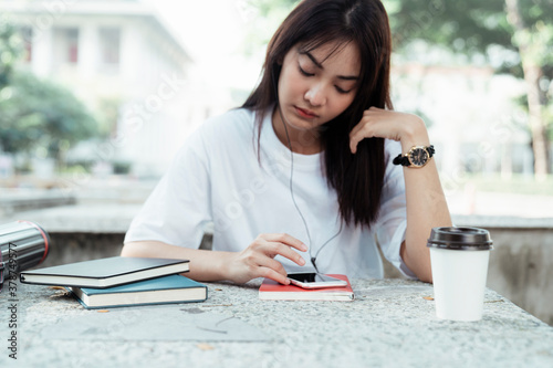 University student listen to musich with earphones and smartphone at park.