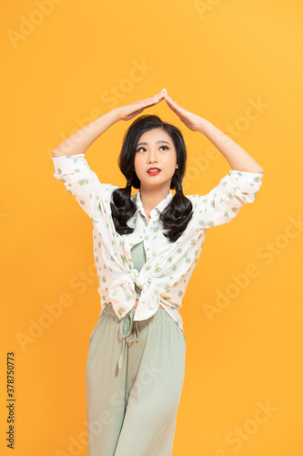 Photo of nice pleased woman in raincoat making roof gesture and smiling isolated over white background