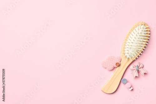 Flat lay composition with modern wooden hair brush on pink background. Space for text