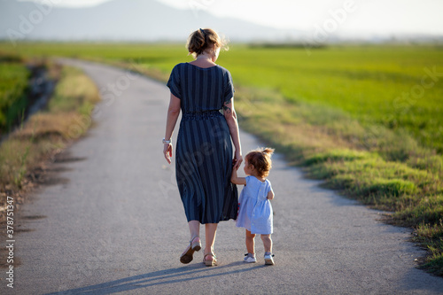 Obraz na płótnie Madre e hija paseando por camino solitario al atardecer