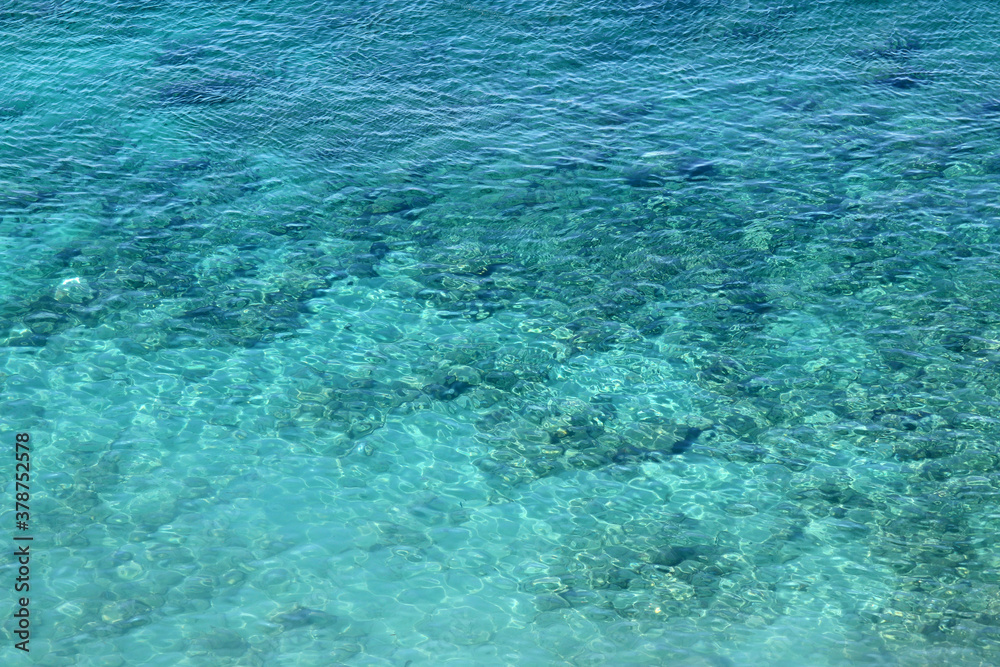 Fototapeta premium Azure water texture, transparent sea surface with a rocky bottom. Aerial view, natural blue background