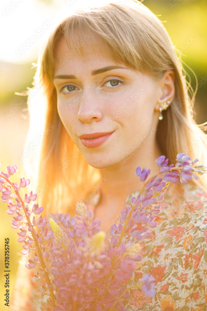 Fototapeta premium Portrait of beautiful blue eyed girl with lupin flowers 