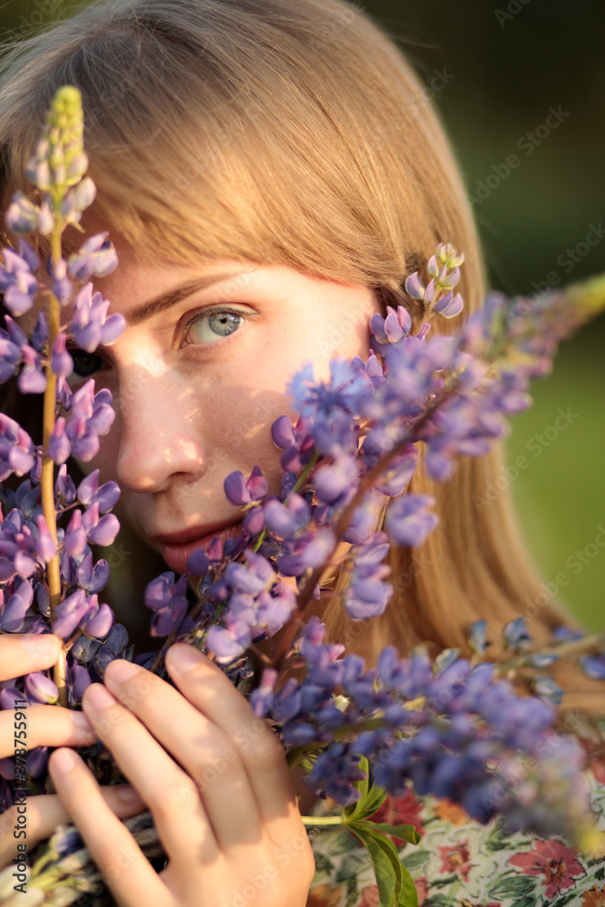 Portrait of beautiful blue eyed girl with lupin flowers 
