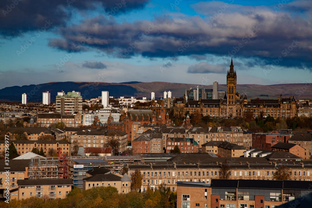 Glasgow / Scotland - Nov 13, 2013: City sunset fall panorama view. University of Glasgow and mountains. Blue sky with clouds.