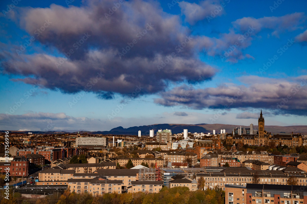Glasgow / Scotland - Nov 13, 2013: City sunset fall panorama view. University of Glasgow and mountains. Blue sky with clouds..