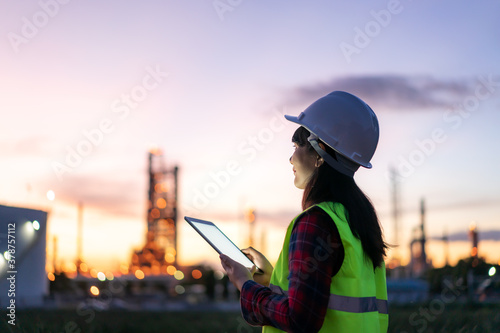 Obraz na płótnie Asian woman petrochemical engineer working at night with digital tablet Inside oil and gas refinery plant industry factory at night for inspector safety quality control