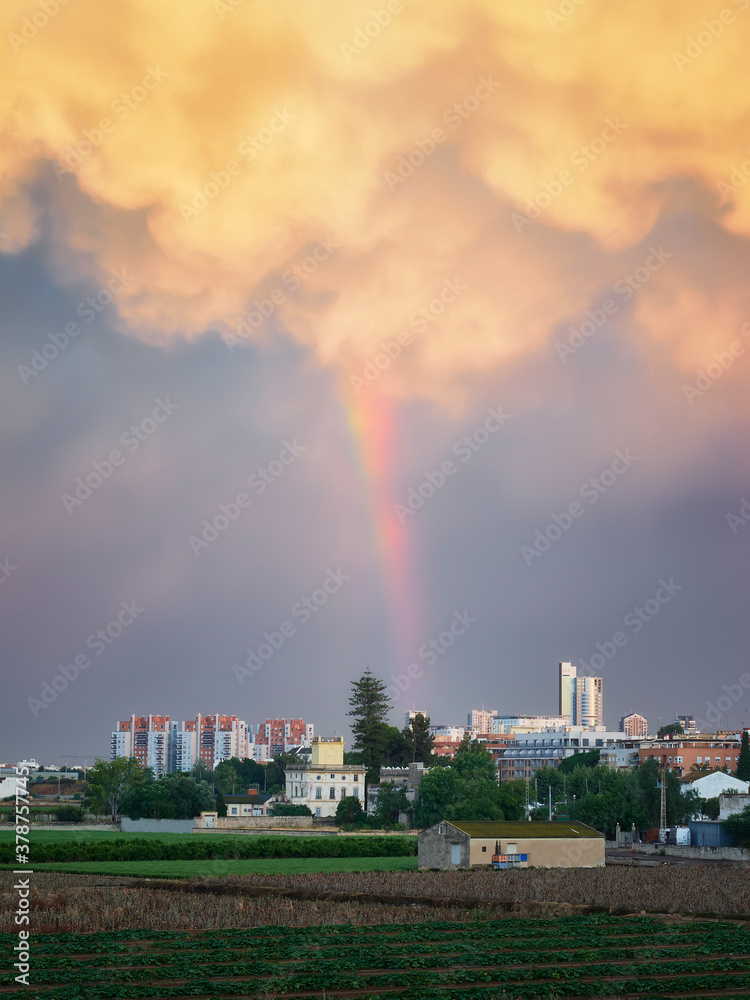 bello arcoiris con nube dramatica en el skyline y campos de Valencia y Burjasot,España