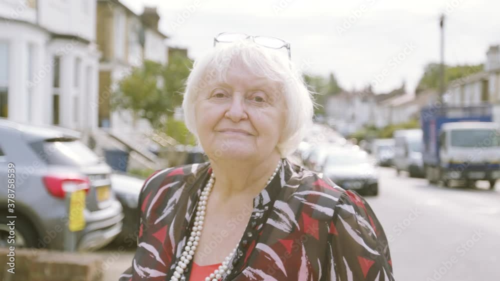 Elderly Woman smiling at camera tilting her head on the street day