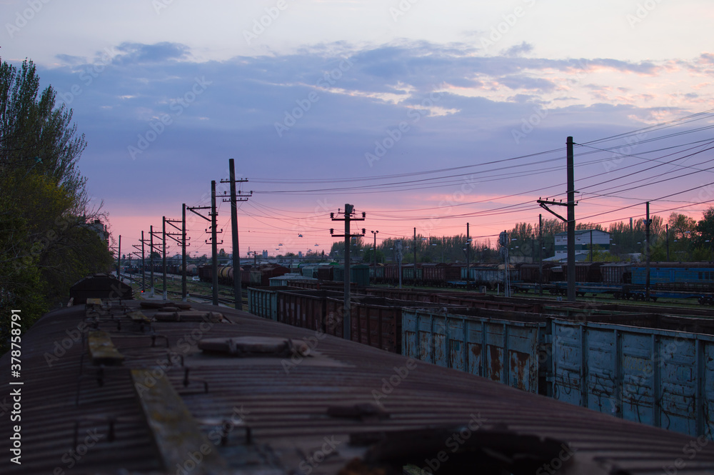 Abandoned old wagons on railway tracks against the backdrop of a beautiful sunset.