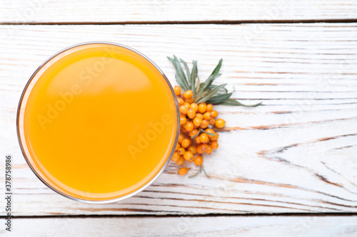 Delicious sea buckthorn juice and fresh berries on white wooden table, top view. Space for text