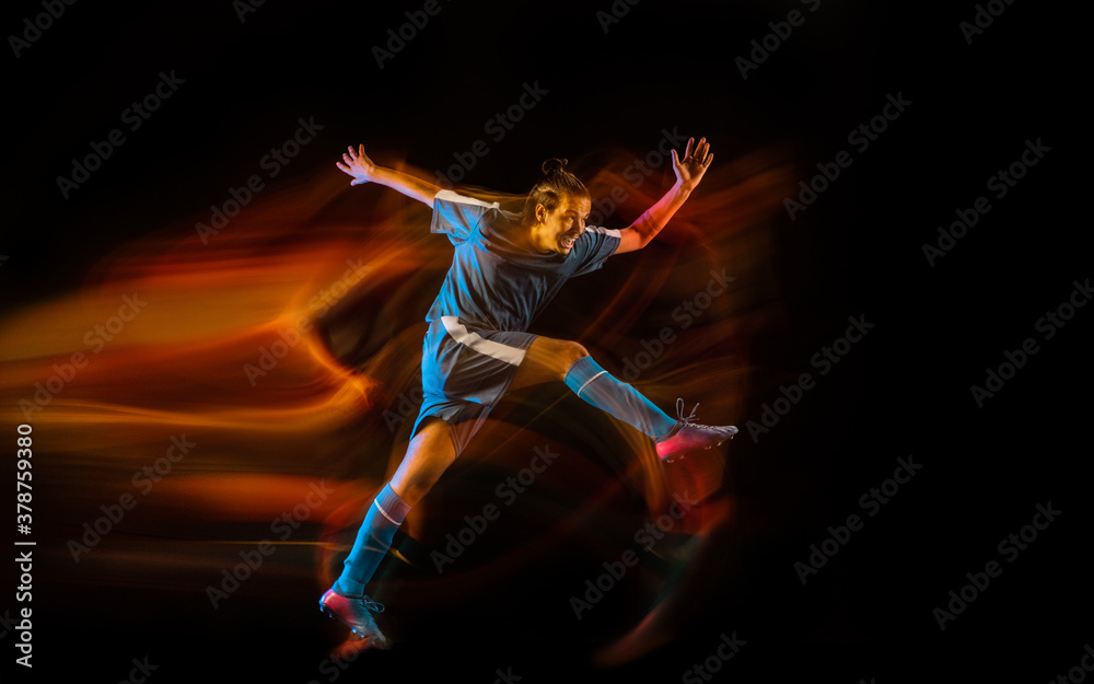 Motion. Football or soccer player on black studio background in mixed light. Young male sportive model training in action. Kicking ball, attacking, catching. Concept of sport, competition, winning. Motion. Football or soccer player on black studio background in mixed light. Young male sportive model training in action. Kicking ball, attacking, catching. Concept of sport, competition, winning.