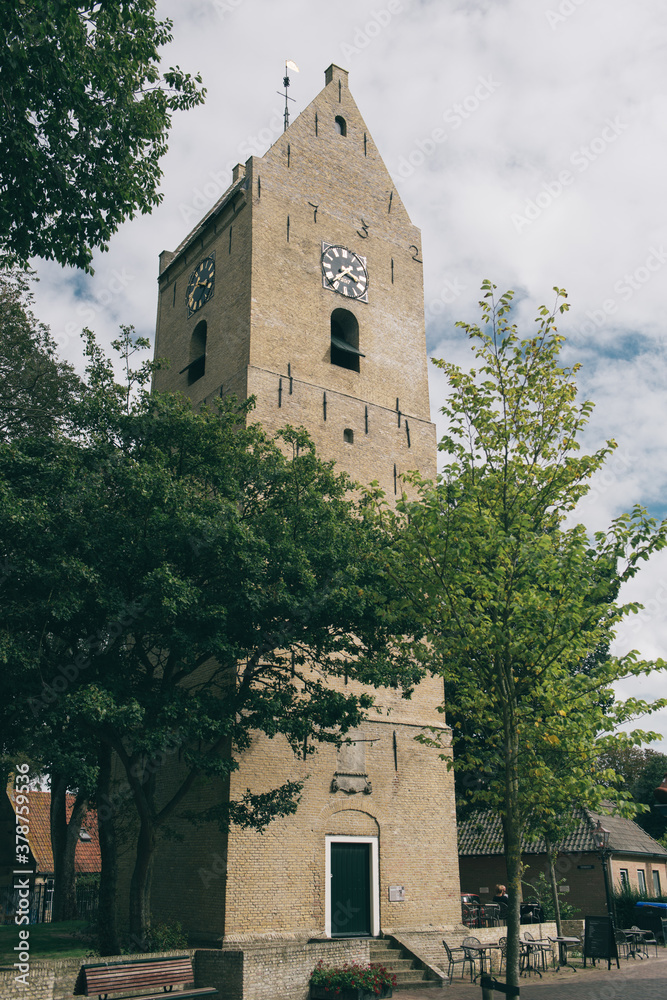 Fototapeta premium Church tower on Ameland in Nes with some trees in front of it
