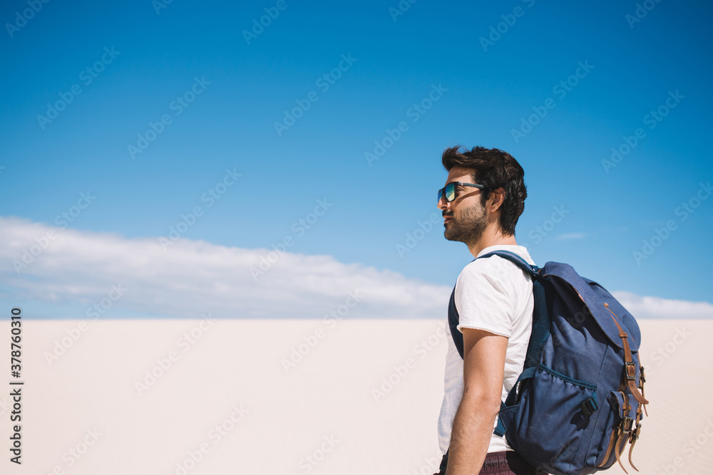 Male traveler enjoying beautiful scenery in White sands national monument during hot day, South Asian tourist in sunglasses exploring dune in desert looking at skyline over dry surface of landmark Male traveler enjoying beautiful scenery in White sands national monument during hot day, South Asian tourist in sunglasses exploring dune in desert looking at skyline over dry surface of landmark