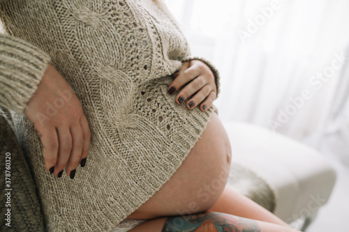 Сloseup, pregnant woman sitting on the couch