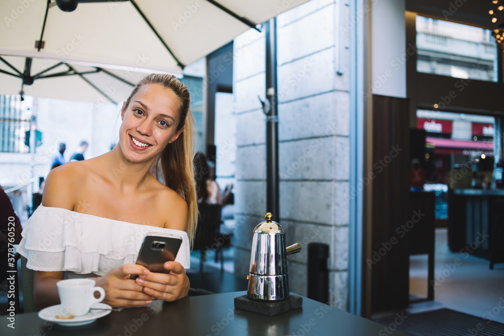 Smiling woman using smartphone in cafe