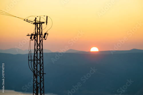 High voltage towers on coast at sunset
