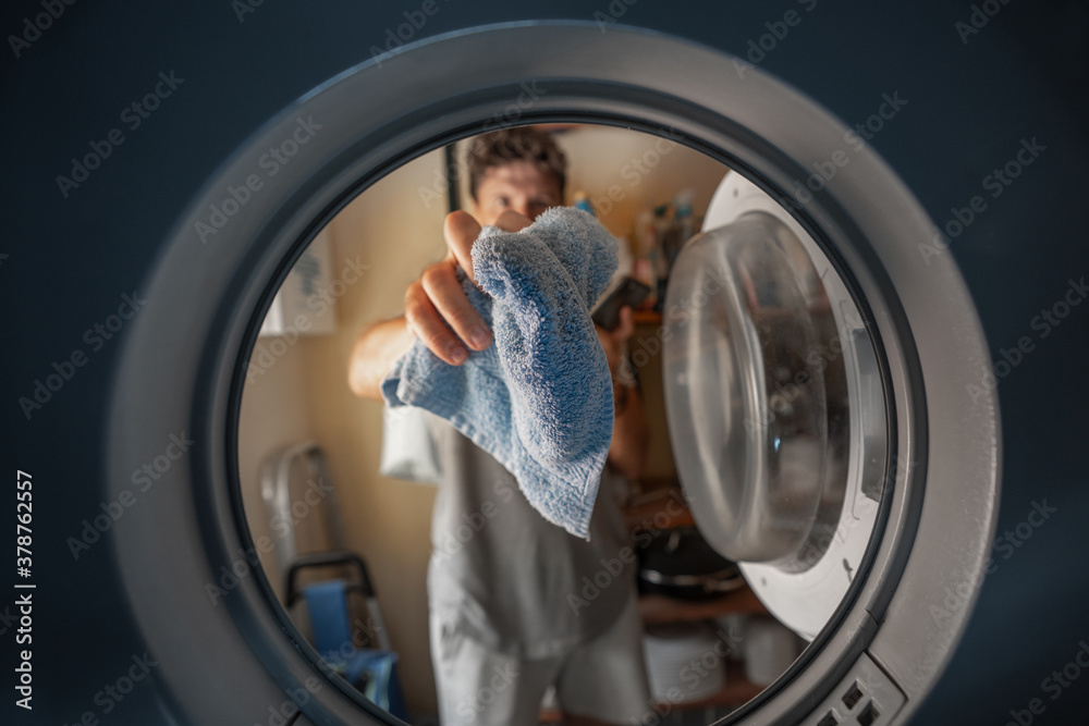 man putting a towel in a washing machine man putting a towel in a washing machine