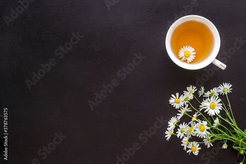 Mug of chamomile tea with fresh flowers top view