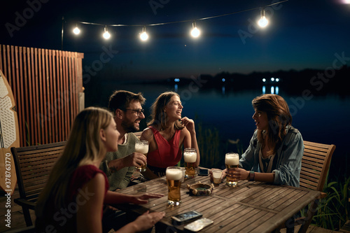 Canvas Print Cheerful company drinking beer in a bar on the lake