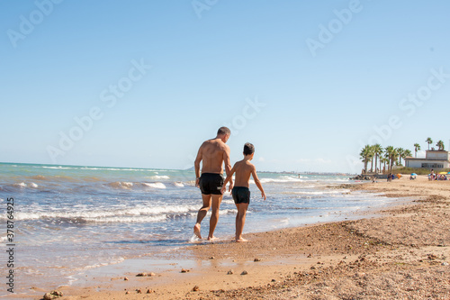 Father walking with a little child on the beach near the sea