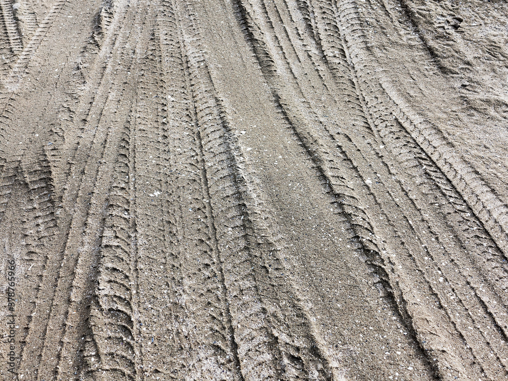 Tyre track and human footprint on sand texture background. Traces of off-road tires. Cracked earth on country road with traces of tires, cars, cracks and dirt. To use as background Tyre track and human footprint on sand texture background. Traces of off-road tires. Cracked earth on country road with traces of tires, cars, cracks and dirt. To use as background