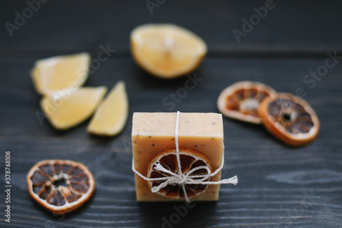 Natural handmade soap with dried slices of oranges on a dark background. Body and skin care. Flat lay. Space for text, top view