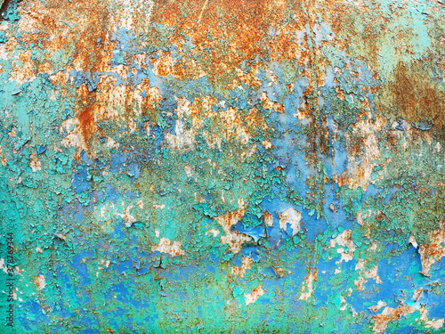 Surface of rusty iron with remnants of old multicolored paint texture background. Rust, corrosion on metal and remnants of blue, green, and white paint. Abstract colored texture