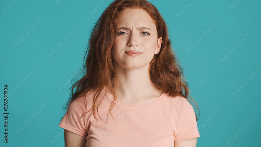 Attractive girl in T-shirt suspiciously looking in camera over colorful background Attractive girl in T-shirt suspiciously looking in camera over colorful background