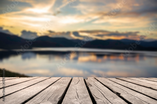 Showcase an old wooden table shelf on a beautiful sunset and blurred nature background. 