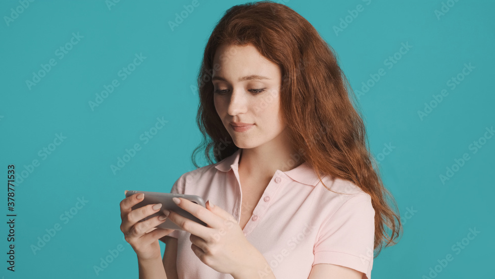 Beautiful concentrated girl watching video on smartphone over colorful background