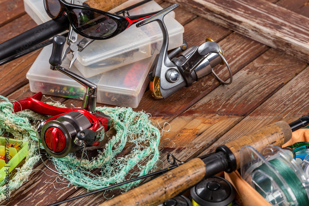 Different fishing tacles with rod and reels on wooden brown background. Different fishing tacles with rod and reels on wooden brown background.