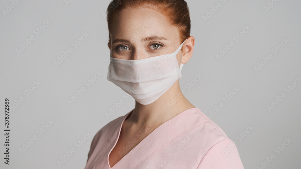 Young doctor in medical mask happily looking in camera over white background. Safety concept Young doctor in medical mask happily looking in camera over white background. Safety concept