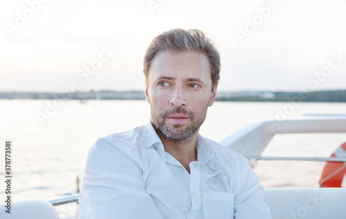 Handsome good looking mature man on the yacht. Portrait of successful man on sailing boat at sunset.