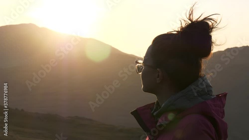 Young woman on top of a mountain overlooking beautiful natural mountain scenery at sunset, peaceful life concept