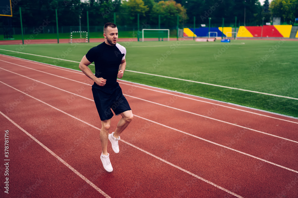 Determined sportsman running on track at stadium